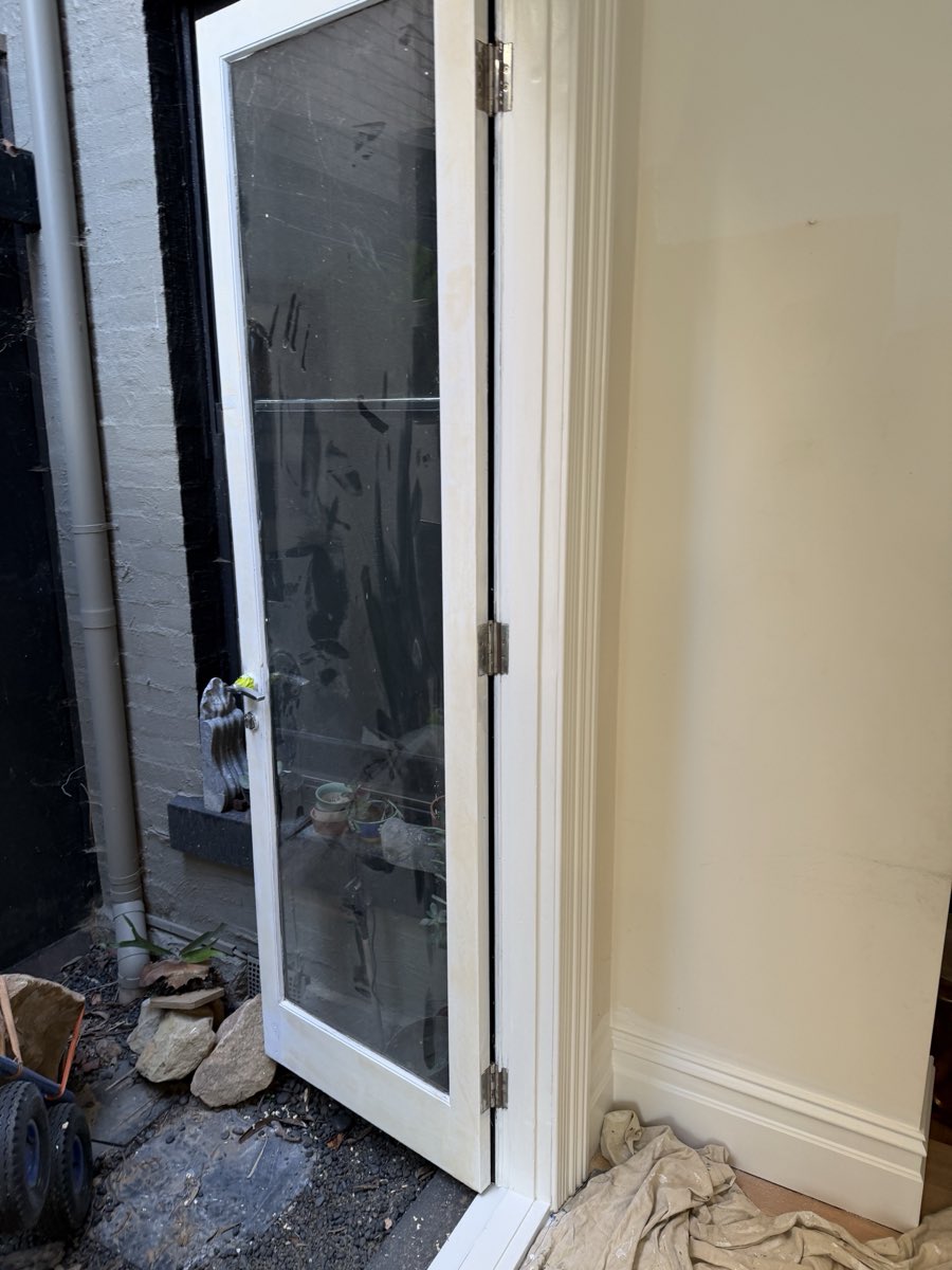 The same doorway at a white coating stage, with the door and architrave covered in a white coat and the surrounding area still under work.