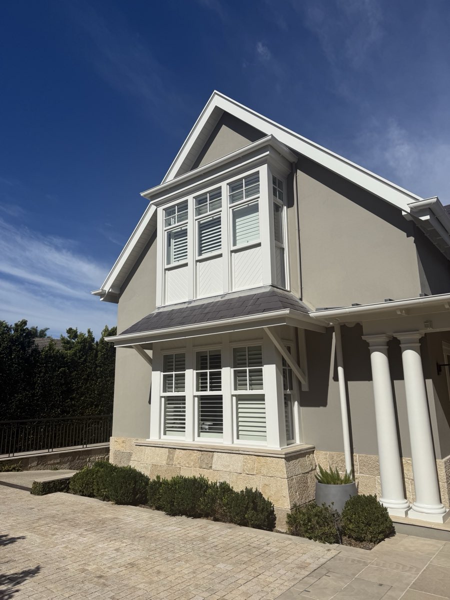 White-painted bay window trim against a grey-painted exterior wall.