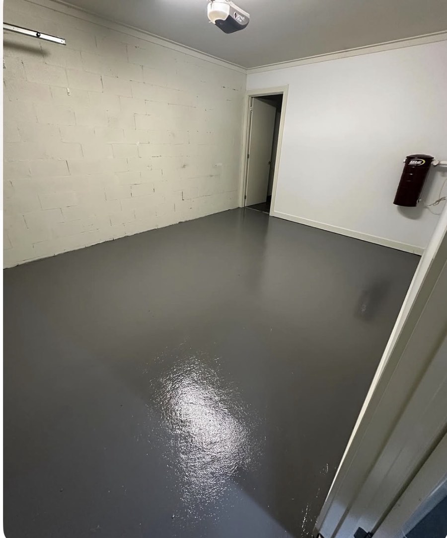 The same garage or utility room after painting, with a grey coated floor and cleaner pale walls around the doorway.