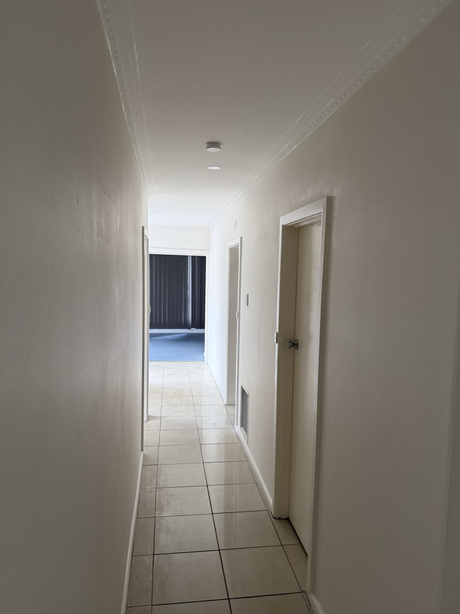 A long light-painted hallway with decorative cornice, tiled floor and multiple doorways.