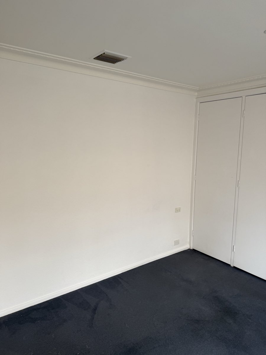 A pale painted wall meets a white door frame beside an adjoining room.