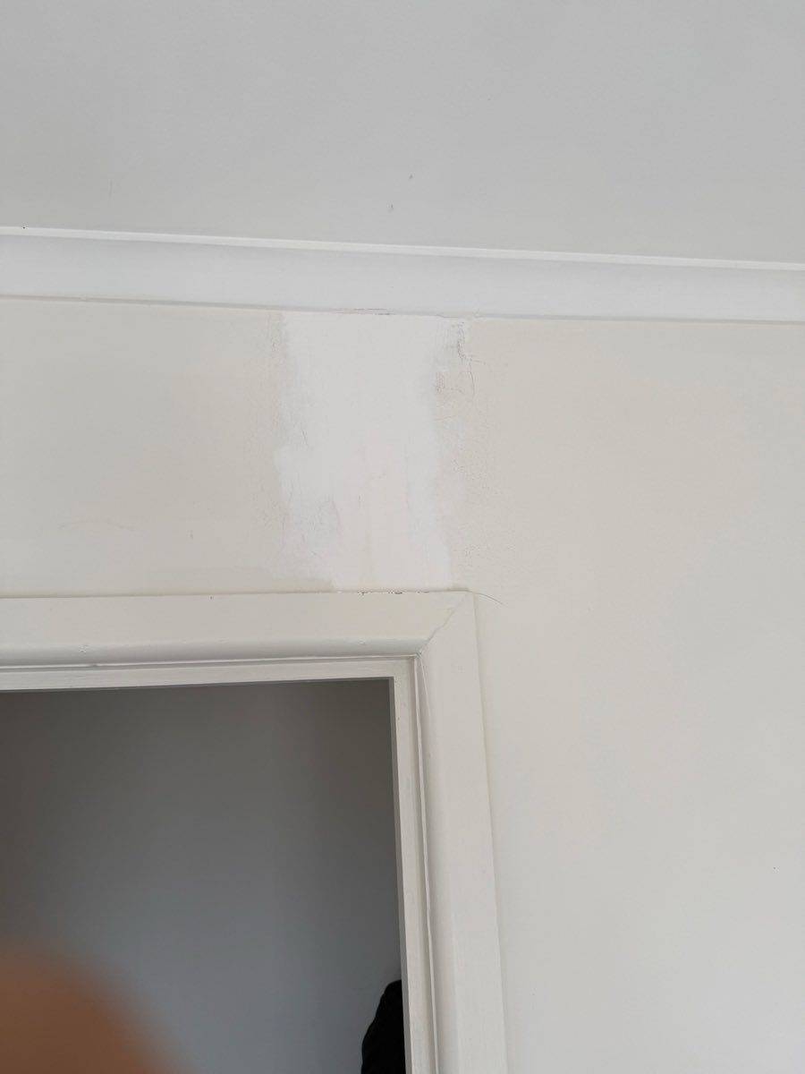 A filled and sanded patch sits on the wall above a white interior doorway.