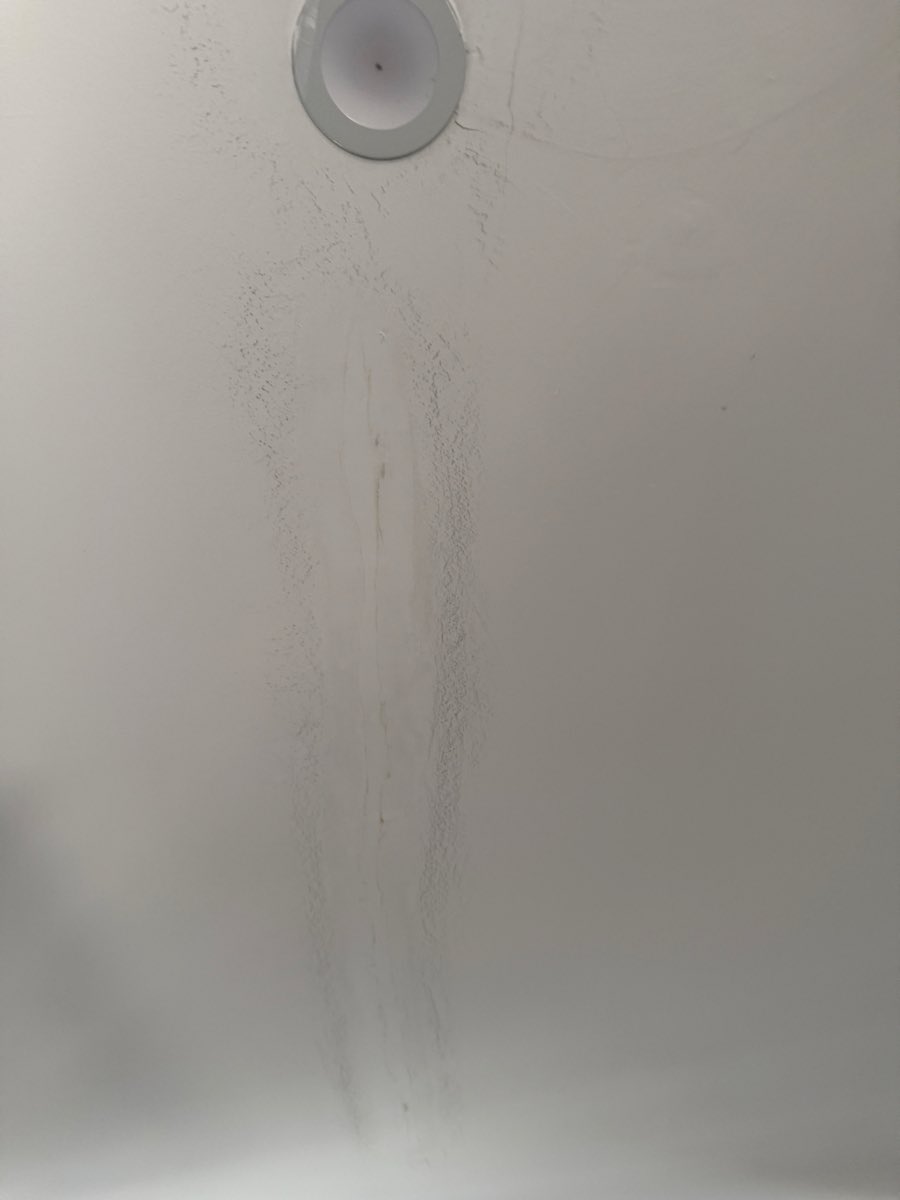 A narrow vertical discoloured streak runs down the wall beneath a circular fitting.