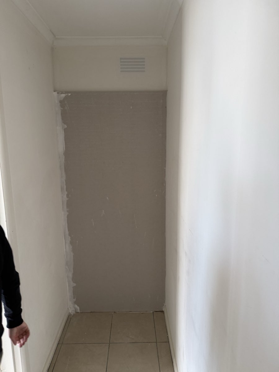 A recessed interior wall has visible joint compound beside a small high vent.